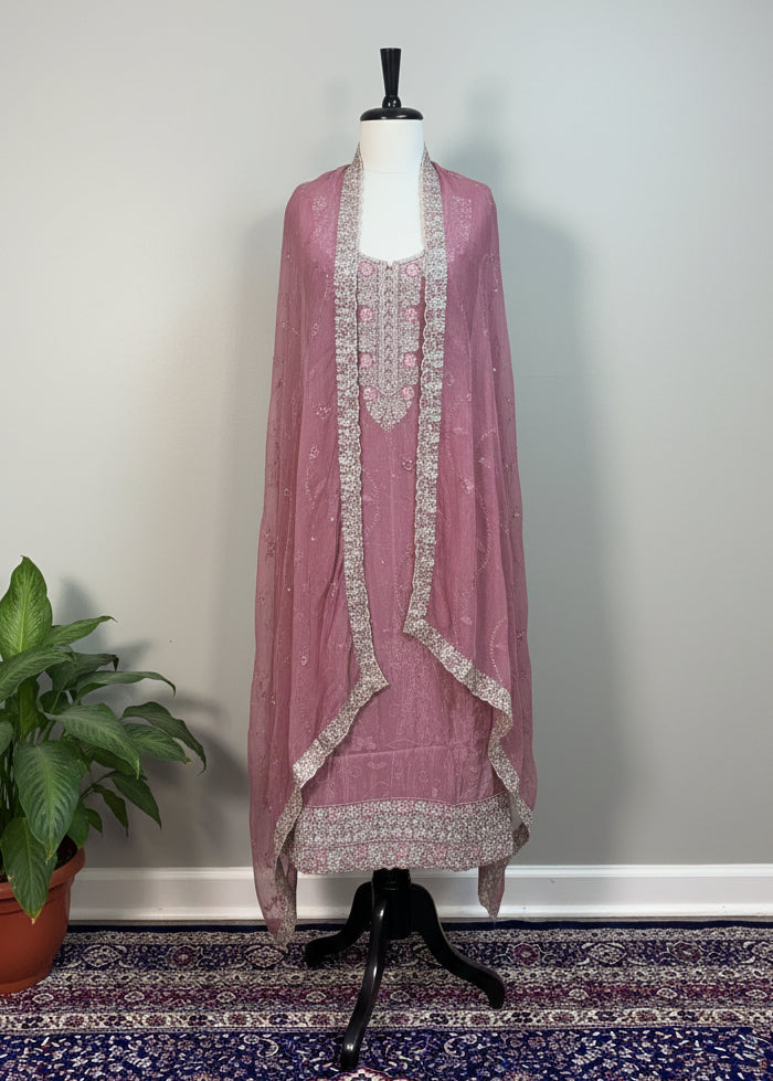 Mauve embroidered dress on a mannequin against a white curtain background