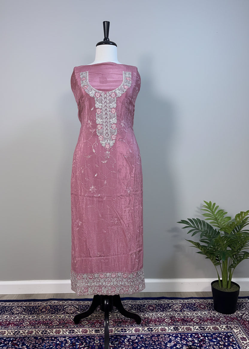 Pink embroidered dress on a mannequin against a beige curtain background