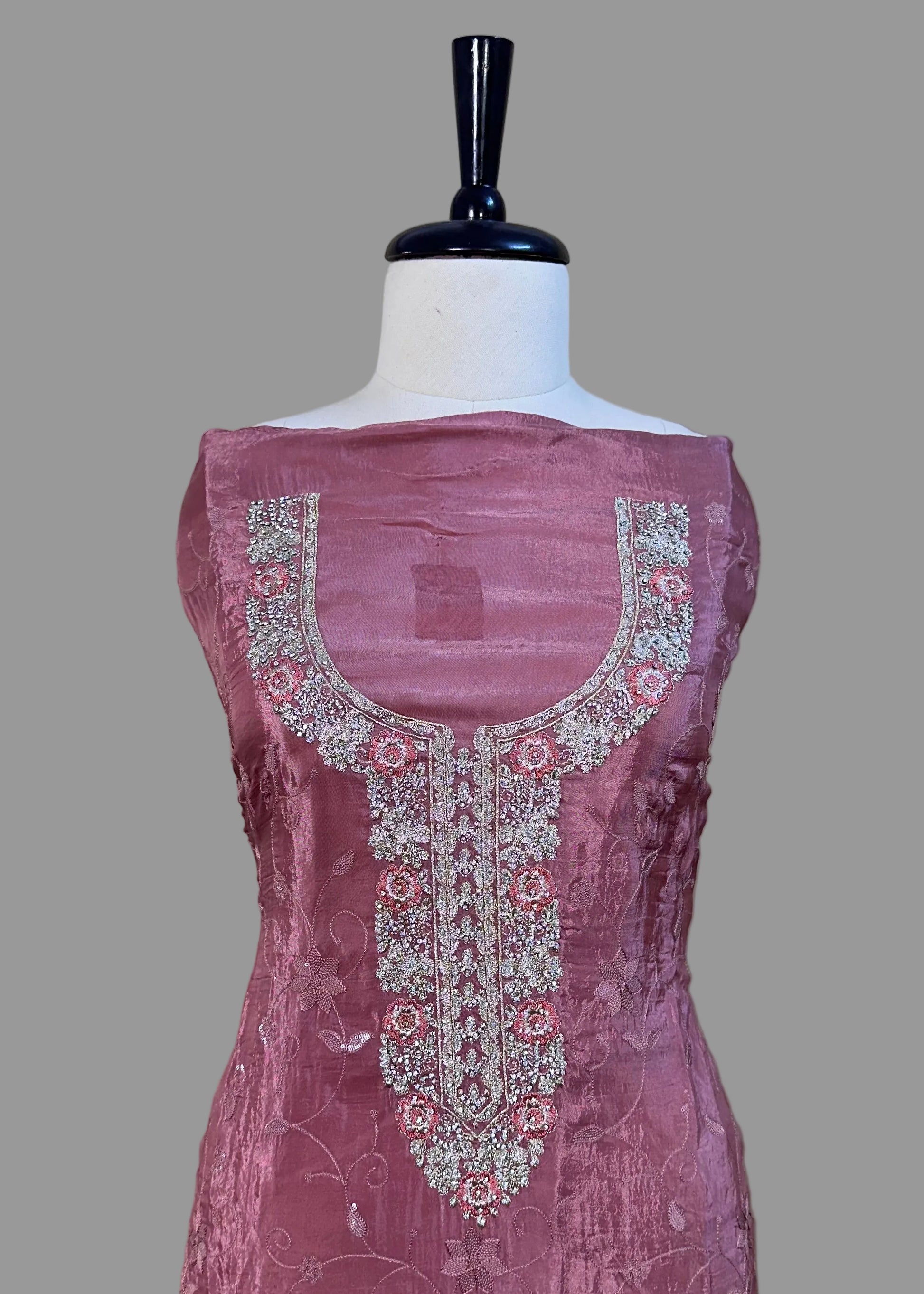 Pink embroidered dress on a mannequin against a beige background
