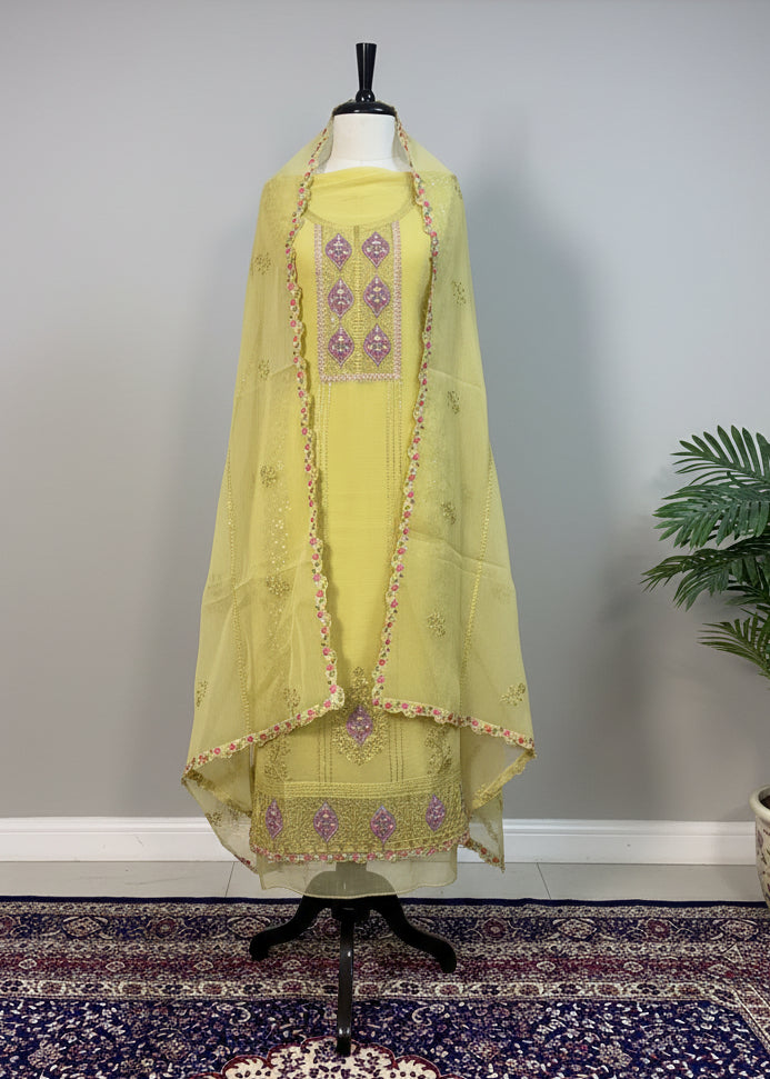 Yellow embroidered traditional outfit on a mannequin against a plain background
