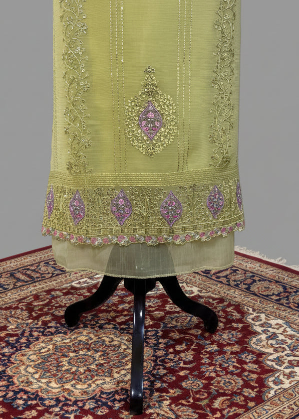 Light green embroidered fabric on a stand with a patterned rug in the background