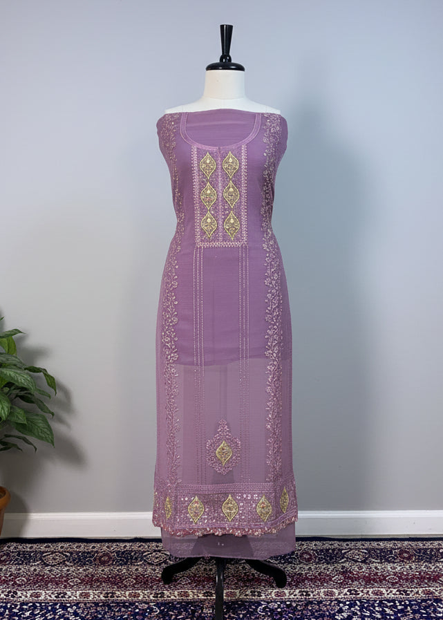 Lavender dress with gold embroidery on a mannequin against a beige curtain.