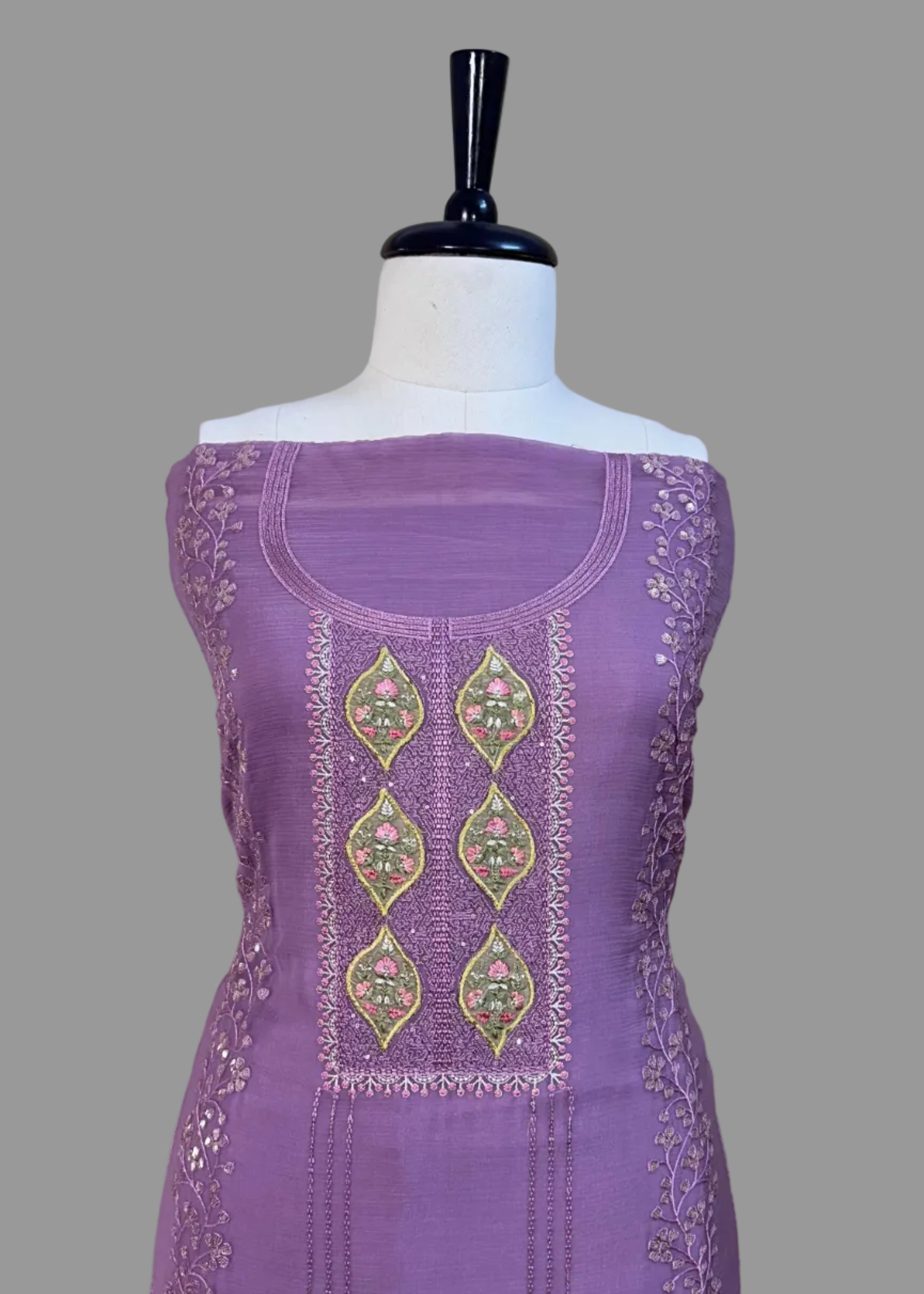 Purple dress with intricate embroidery on a mannequin against a beige background