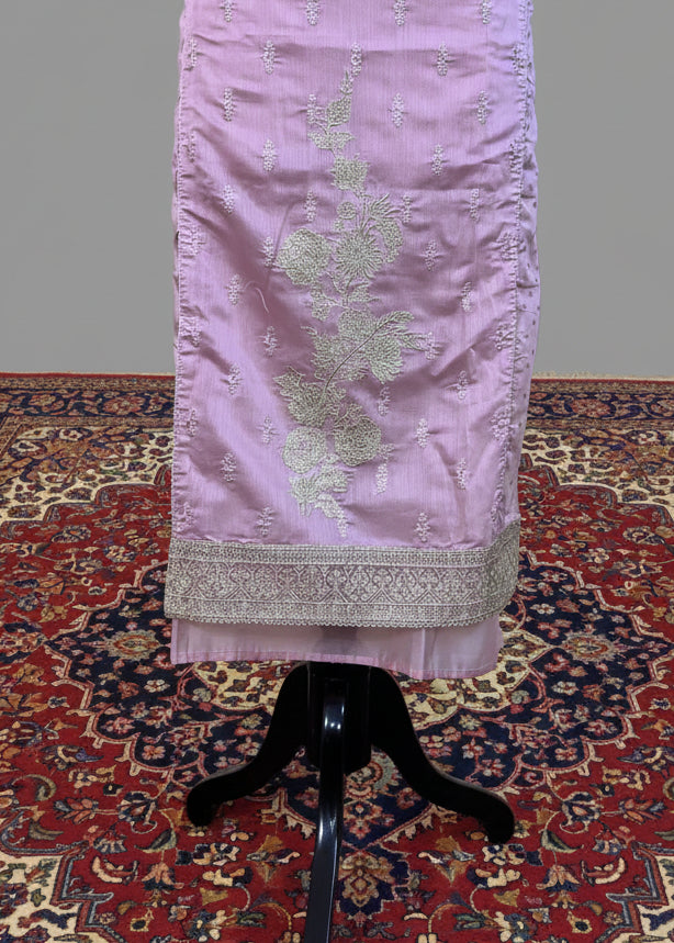 Lavender dress with intricate white embroidery on a stand against a plain background