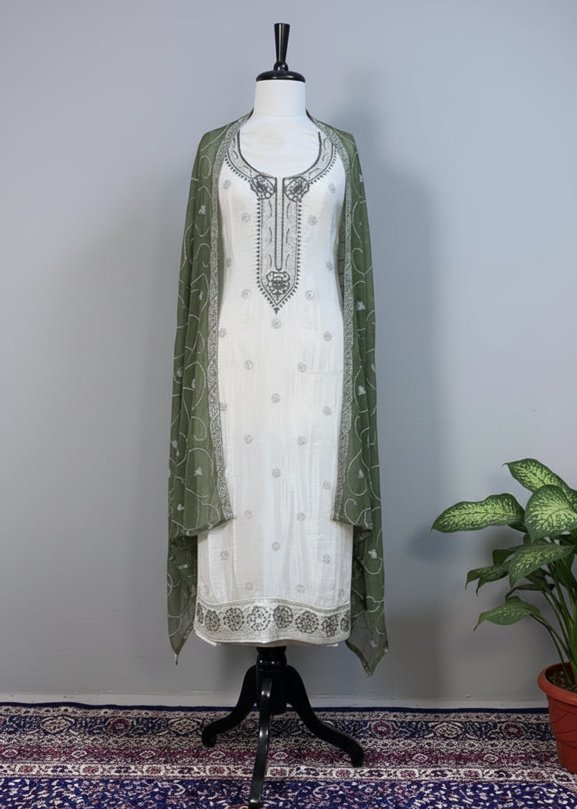 White embroidered dress with green dupatta on a mannequin against a beige background
