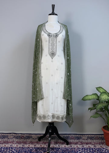 White embroidered dress with green dupatta on a mannequin against a beige background