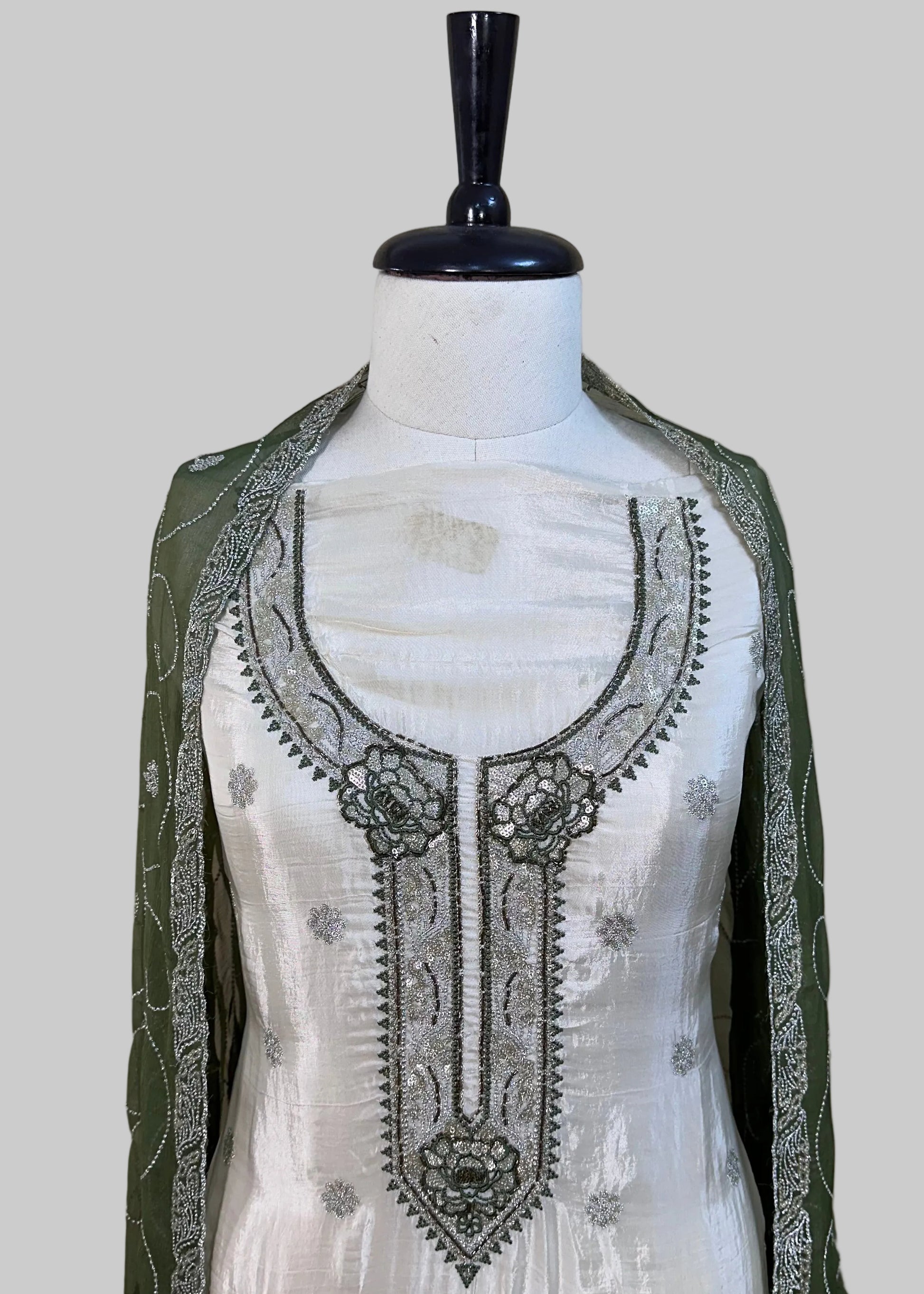 White embroidered dress on a mannequin with a green border against a plain background