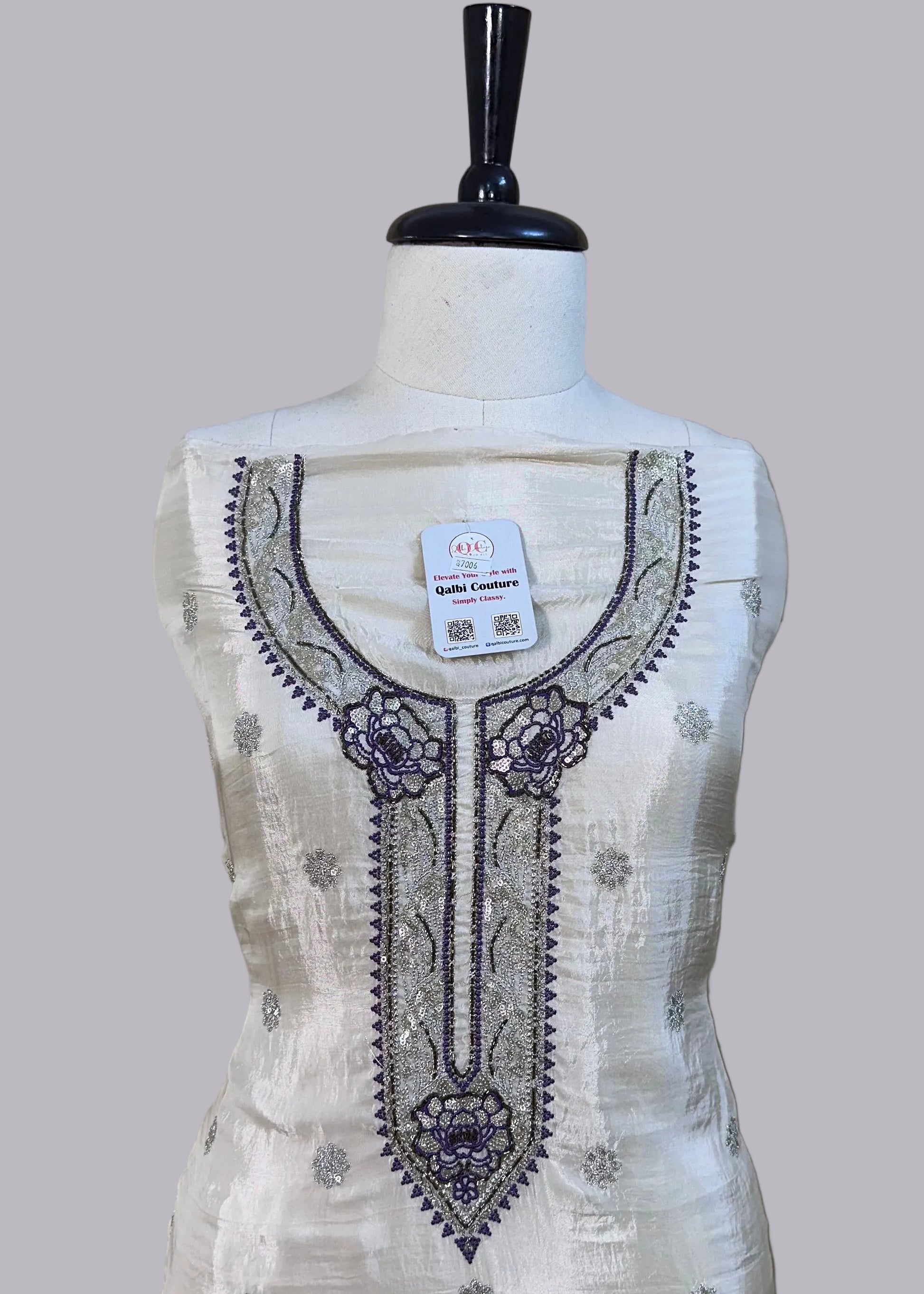 White embroidered dress on a mannequin against a plain background