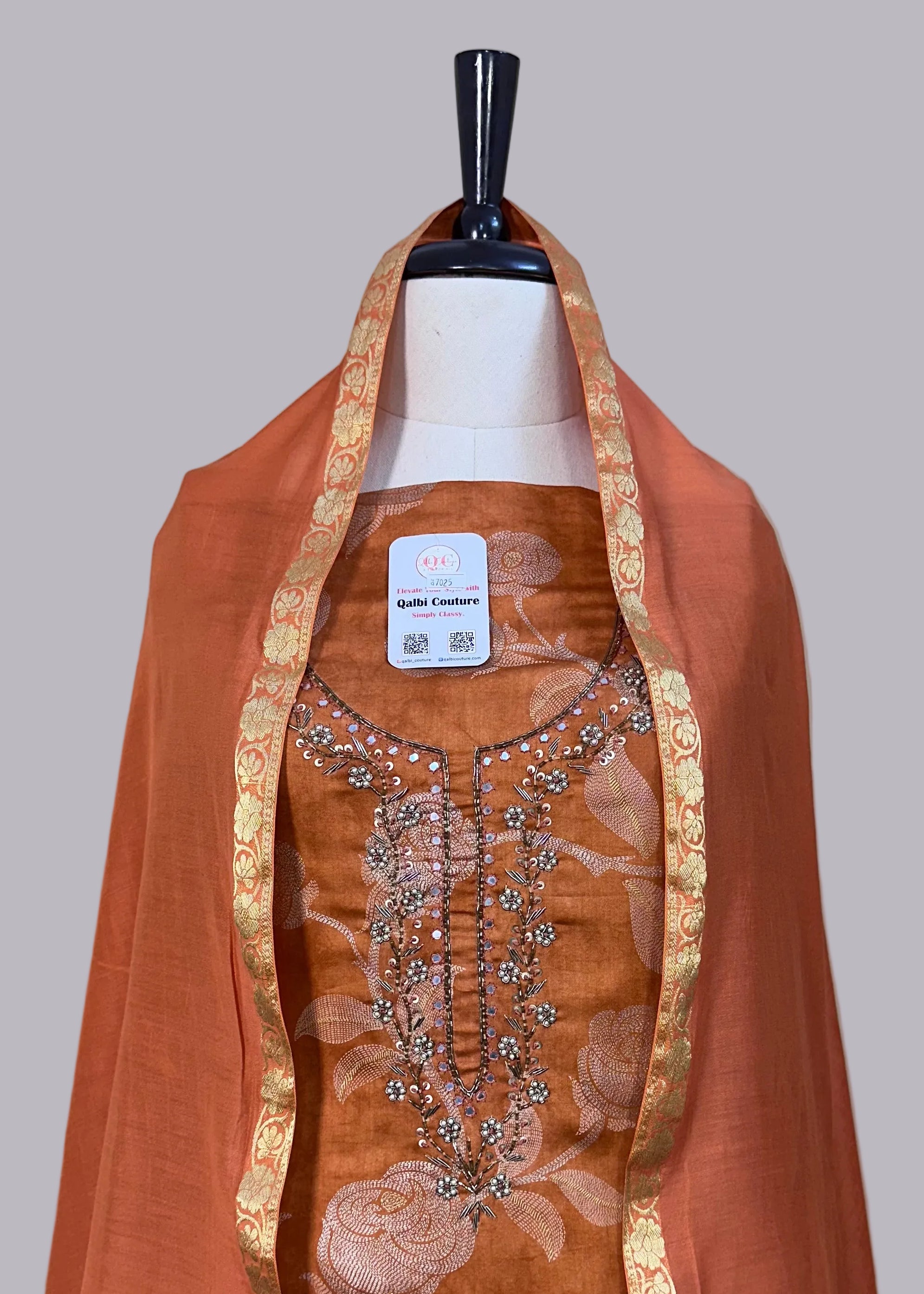 Brown embroidered garment on a mannequin with a plain background