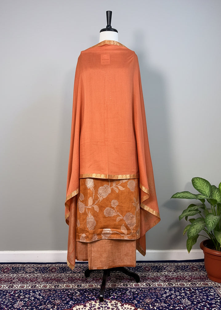 Copper-colored dress on a mannequin against a plain background