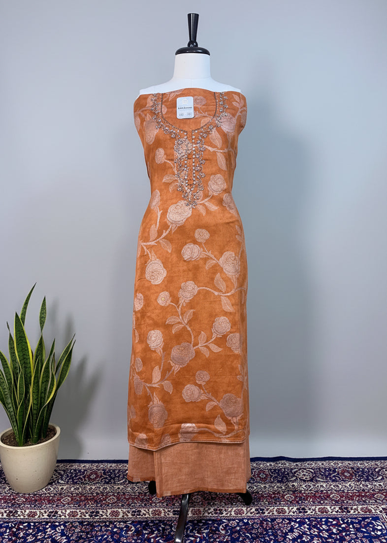 Brown dress with floral patterns on a mannequin against a beige curtain background