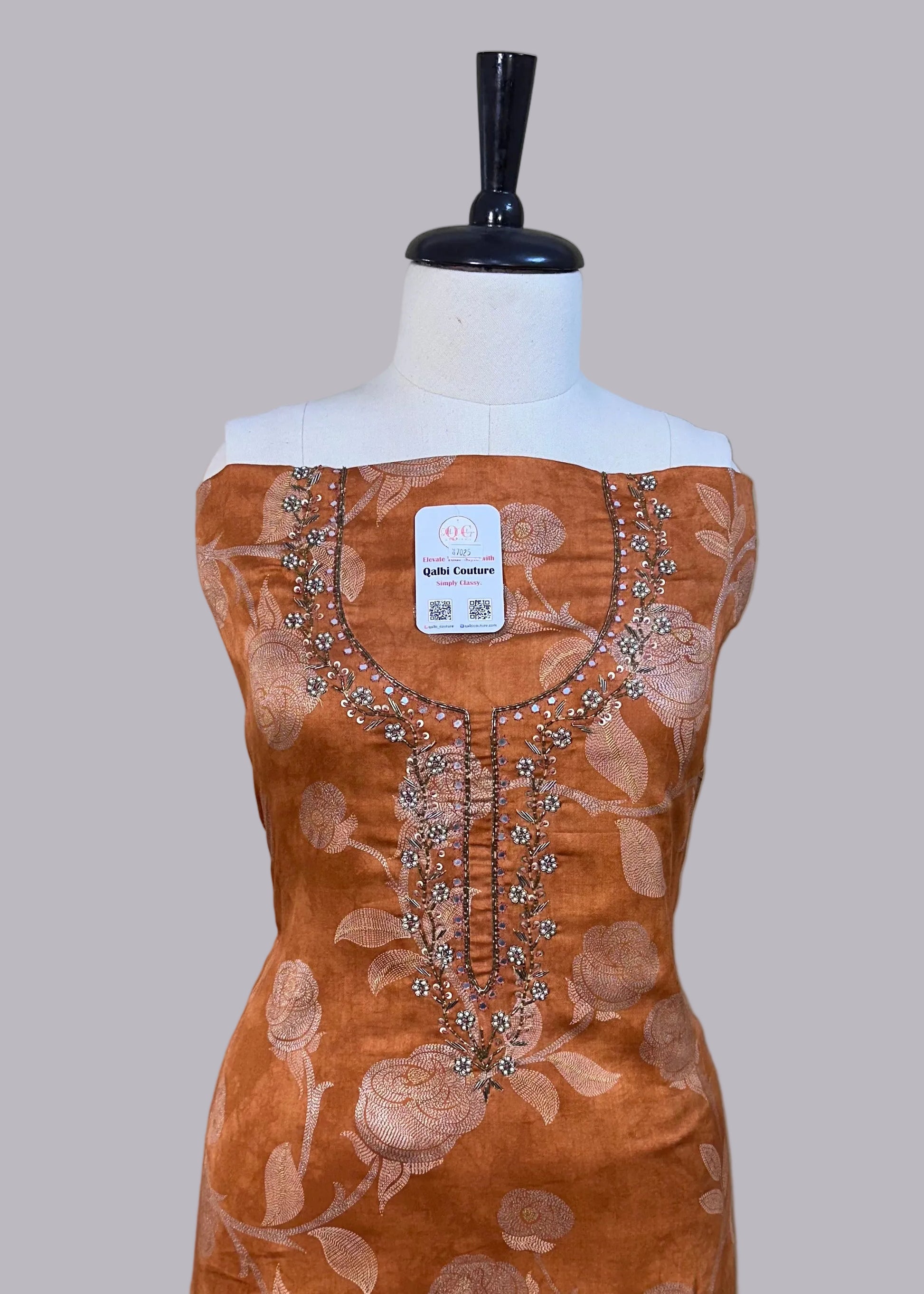 Brown dress with floral patterns on a mannequin against a beige background