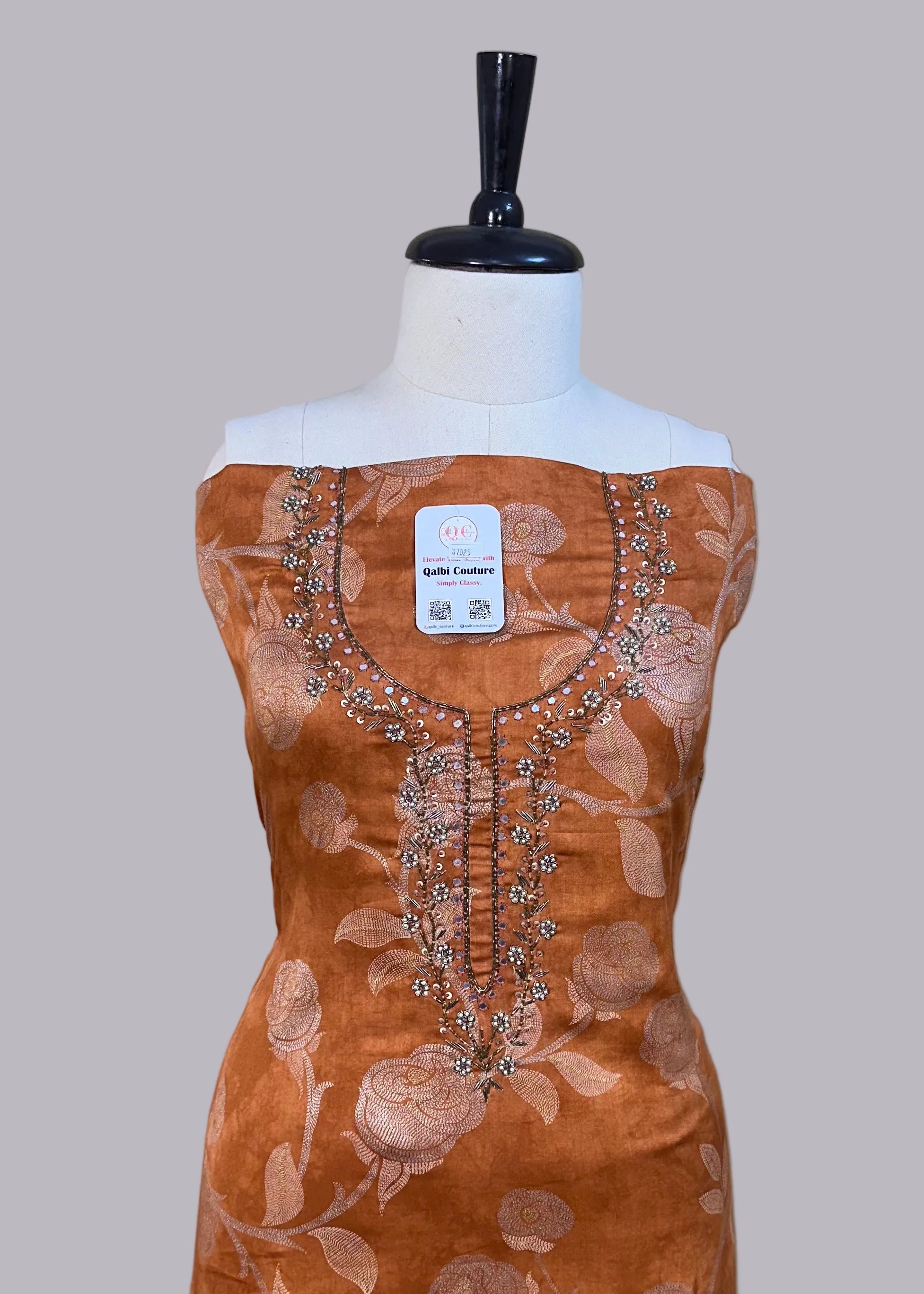 Brown dress with floral patterns on a mannequin against a beige background