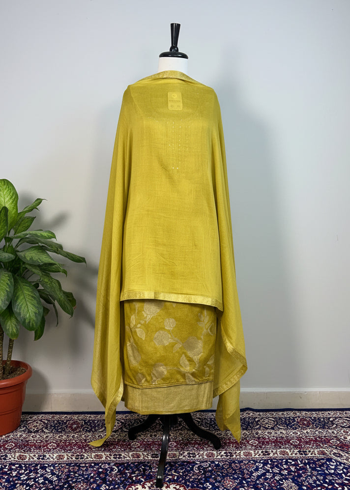 Mannequin wearing a yellow outfit with floral patterns on a patterned rug.