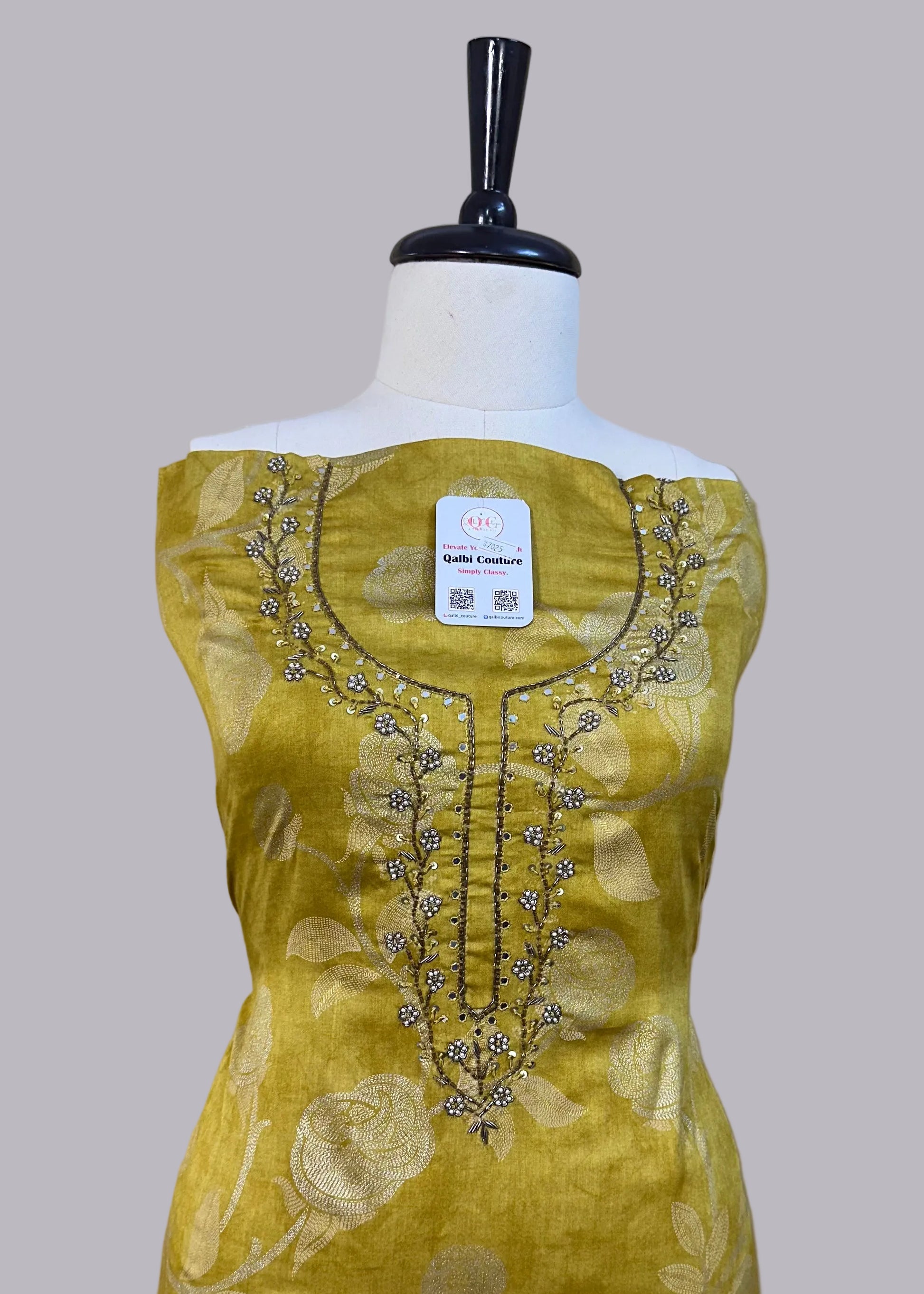 Yellow dress with floral patterns and embroidery on a mannequin against a plain background