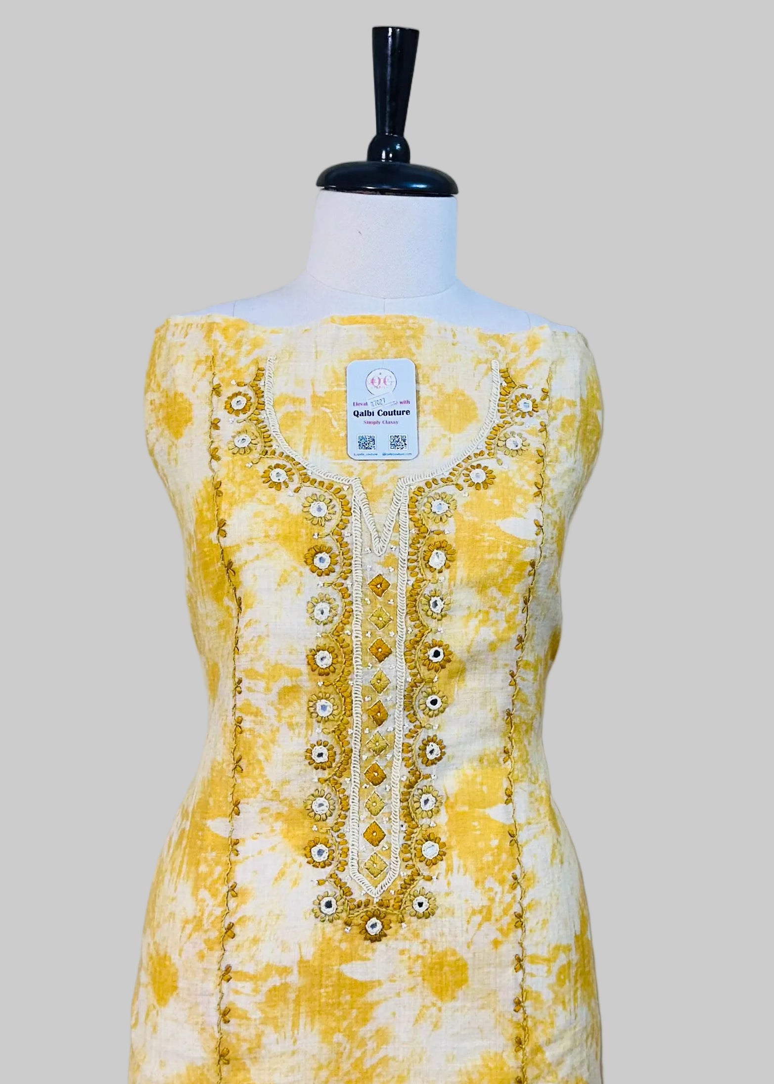 Yellow floral dress on a mannequin against a plain background