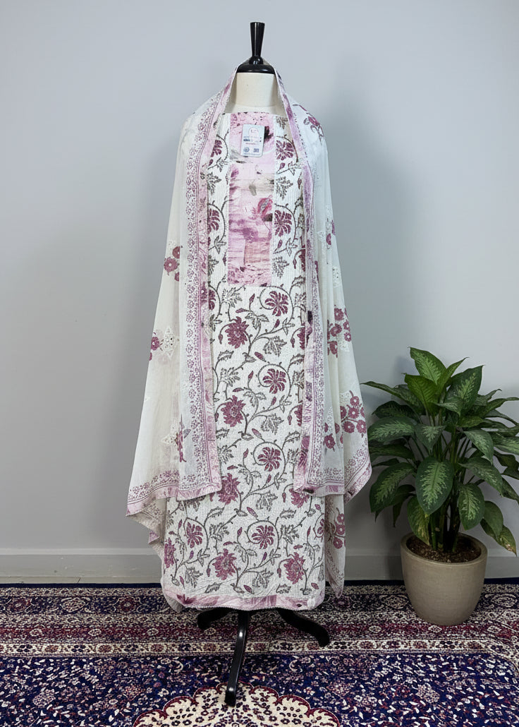 Floral dress on a mannequin against a beige curtain with a patterned rug below.