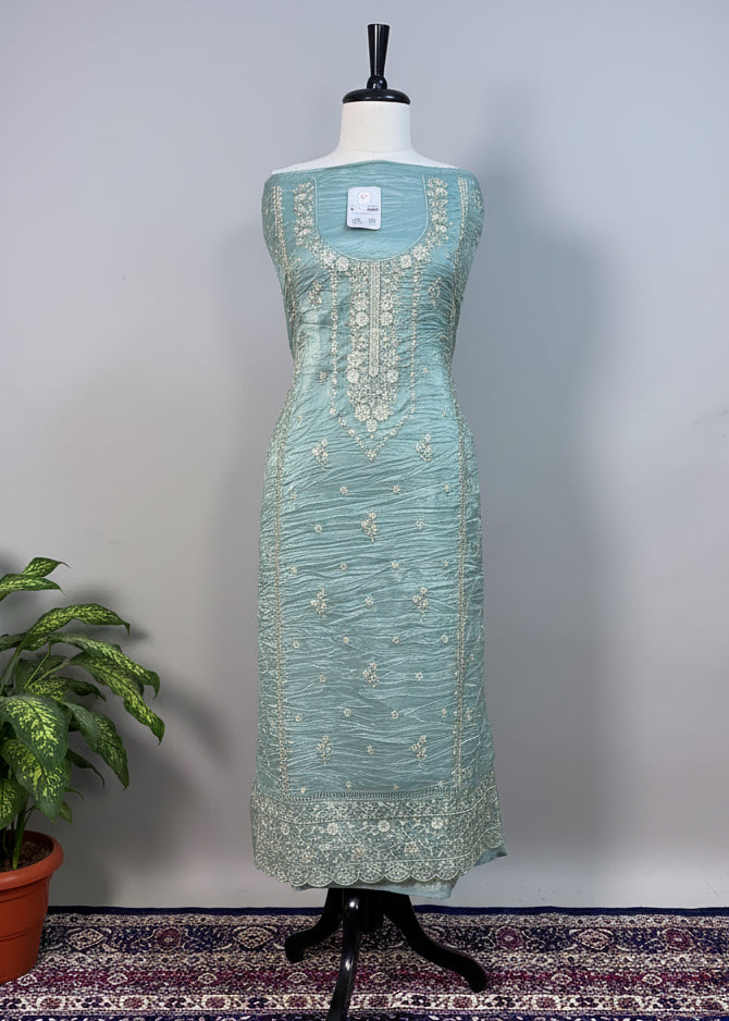 Teal dress on a mannequin against a beige curtain background