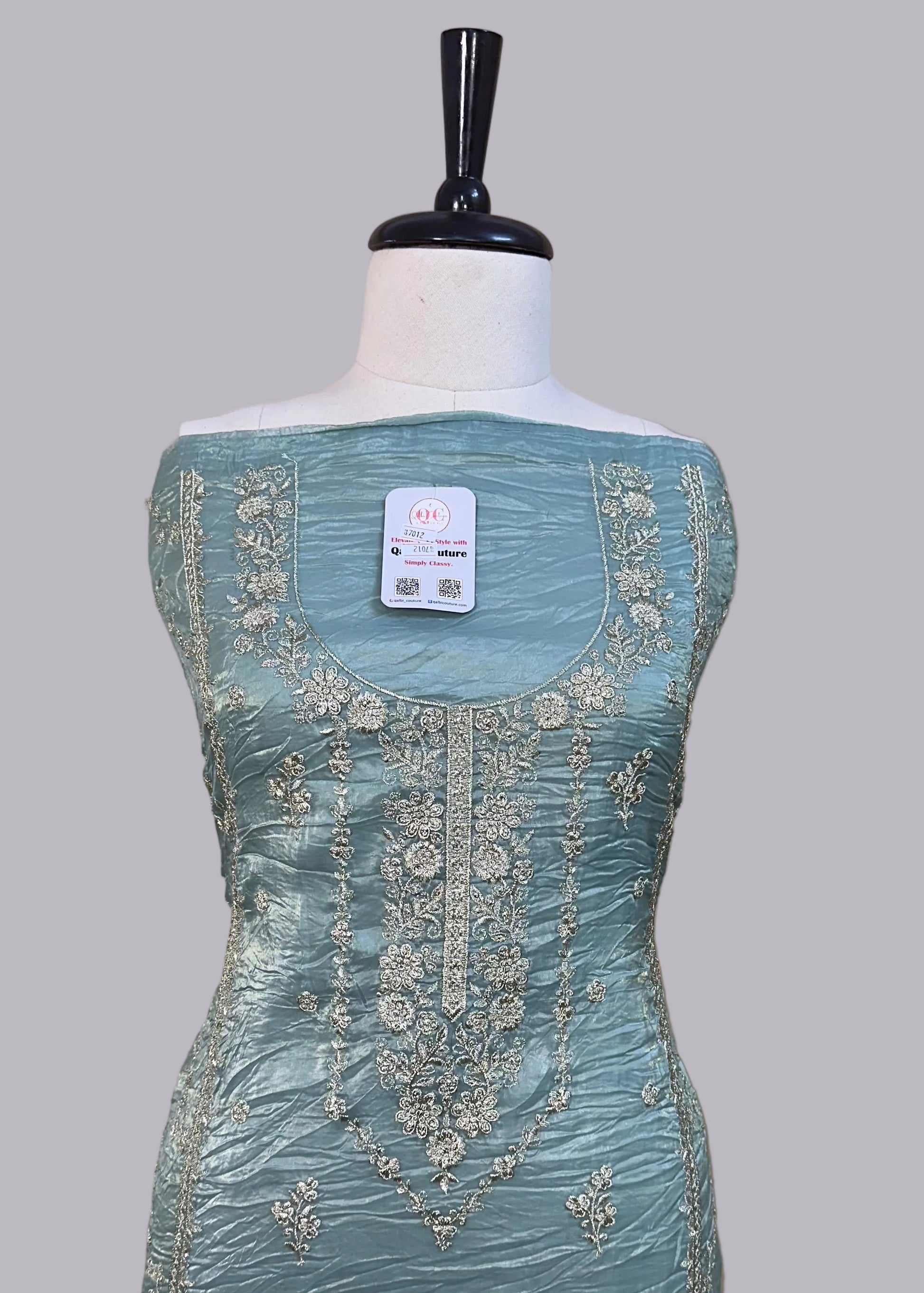Light blue dress with intricate embroidery on a mannequin against a beige background