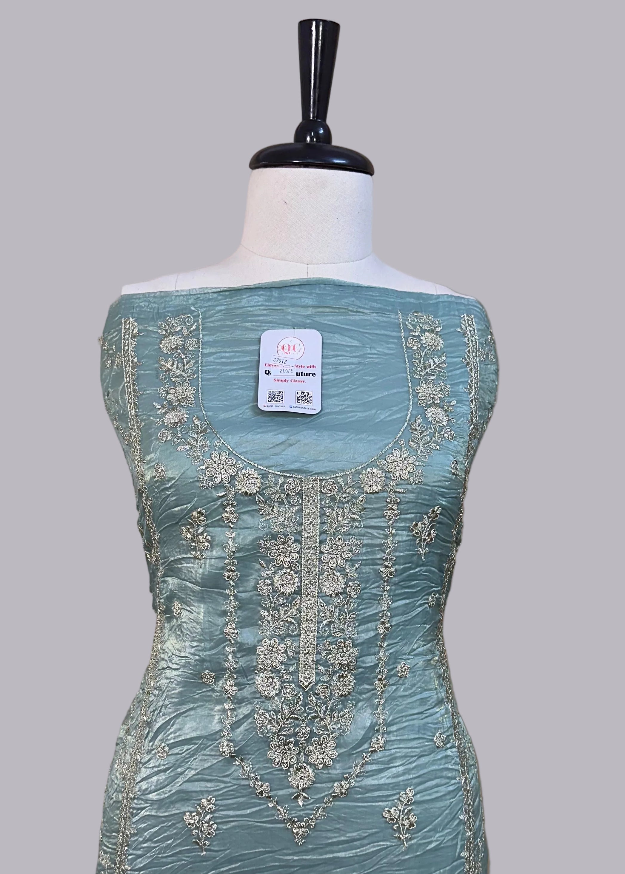 Light blue dress with intricate embroidery on a mannequin against a beige background
