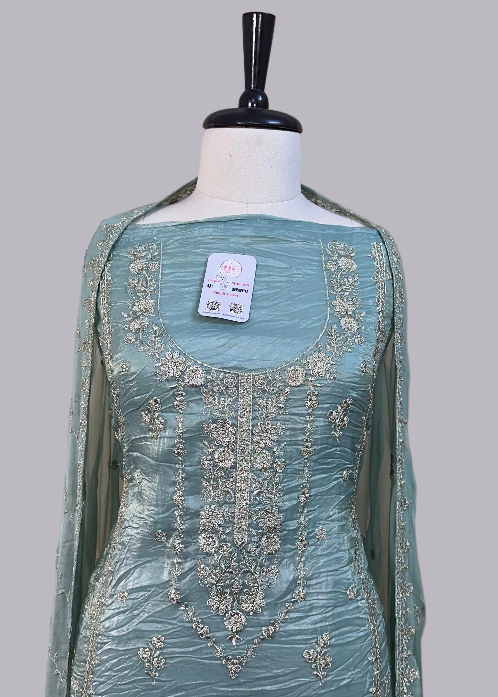 Light blue embroidered dress on a mannequin against a beige background