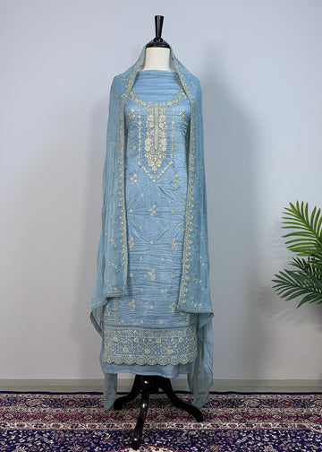 Light blue embroidered traditional outfit on a mannequin against a beige curtain background.