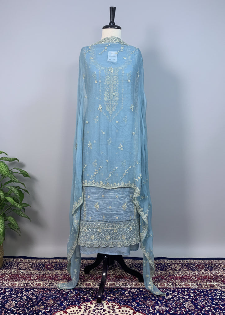 Light blue embroidered dress on a mannequin against a beige curtain background