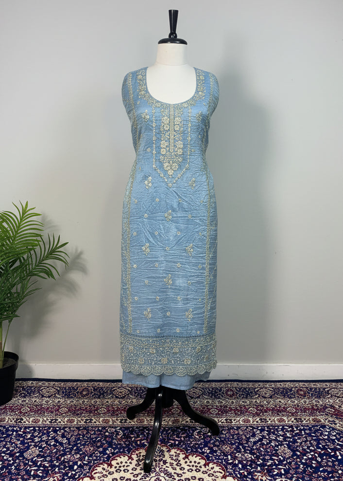Light blue embroidered dress on a mannequin against a beige curtain background