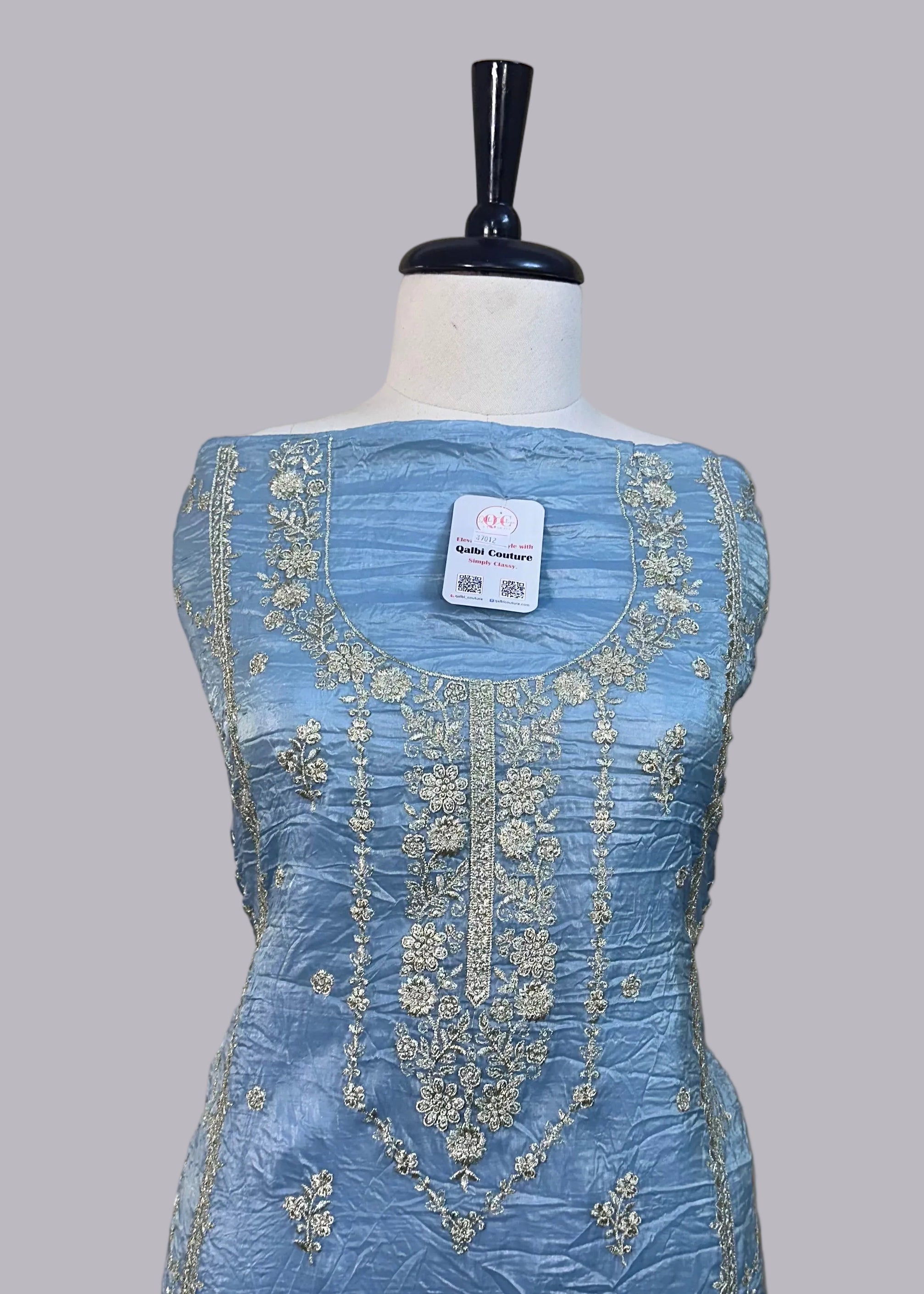 Blue embroidered dress on a mannequin against a beige background