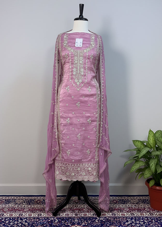 Purple embroidered dress on a mannequin against a beige curtain background