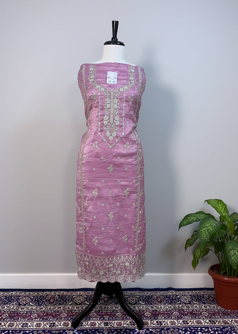 Purple dress on a mannequin against a beige backdrop with a patterned rug at the bottom.