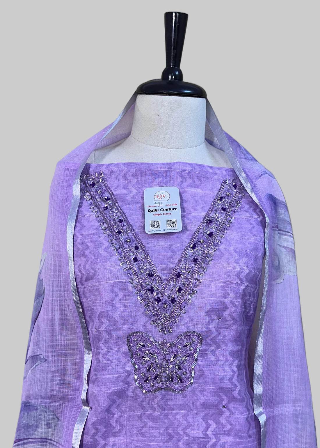 Lavender dress with matching scarf on a mannequin against a beige curtain background.