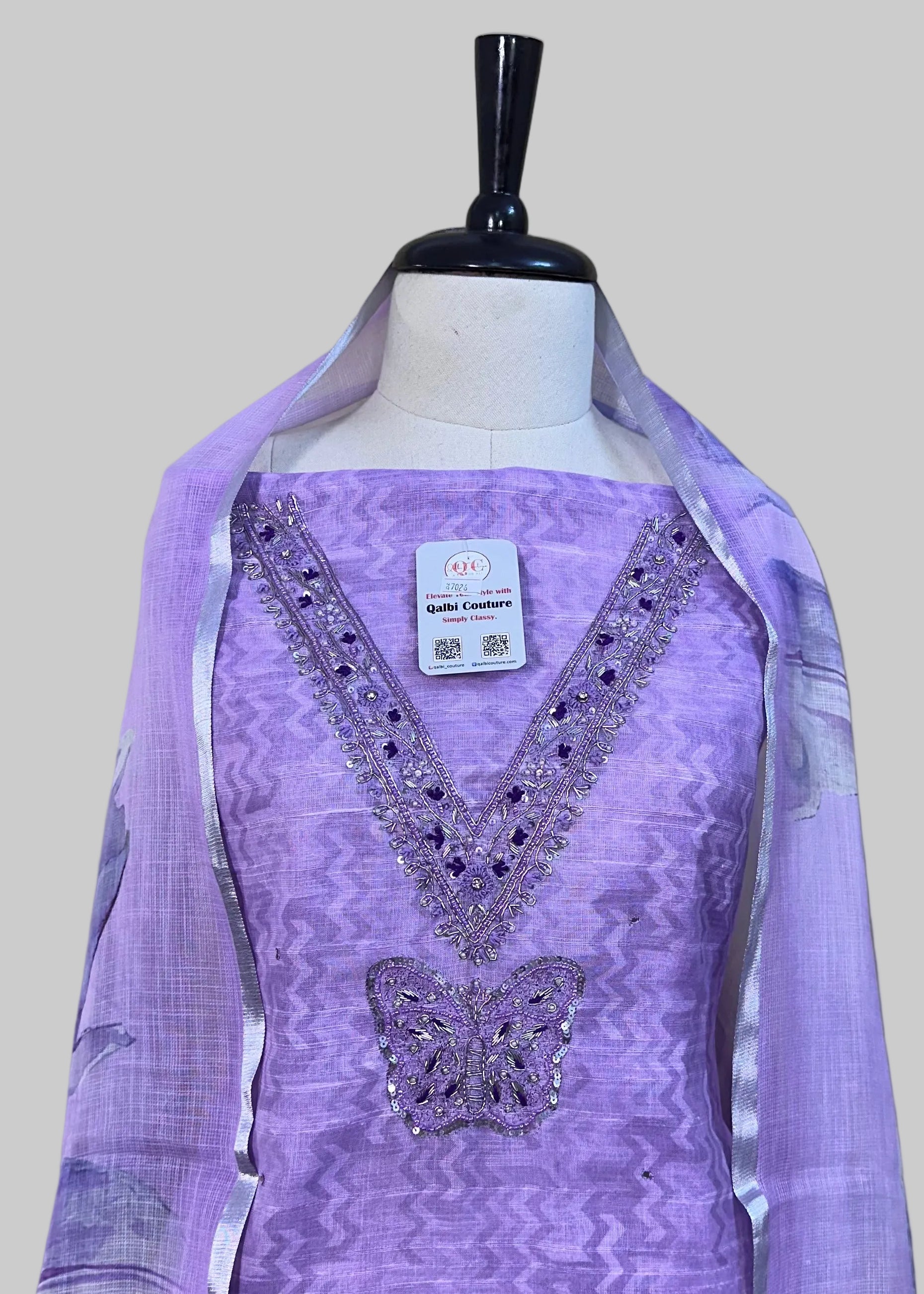 Purple dress with butterfly design on a mannequin against a beige background