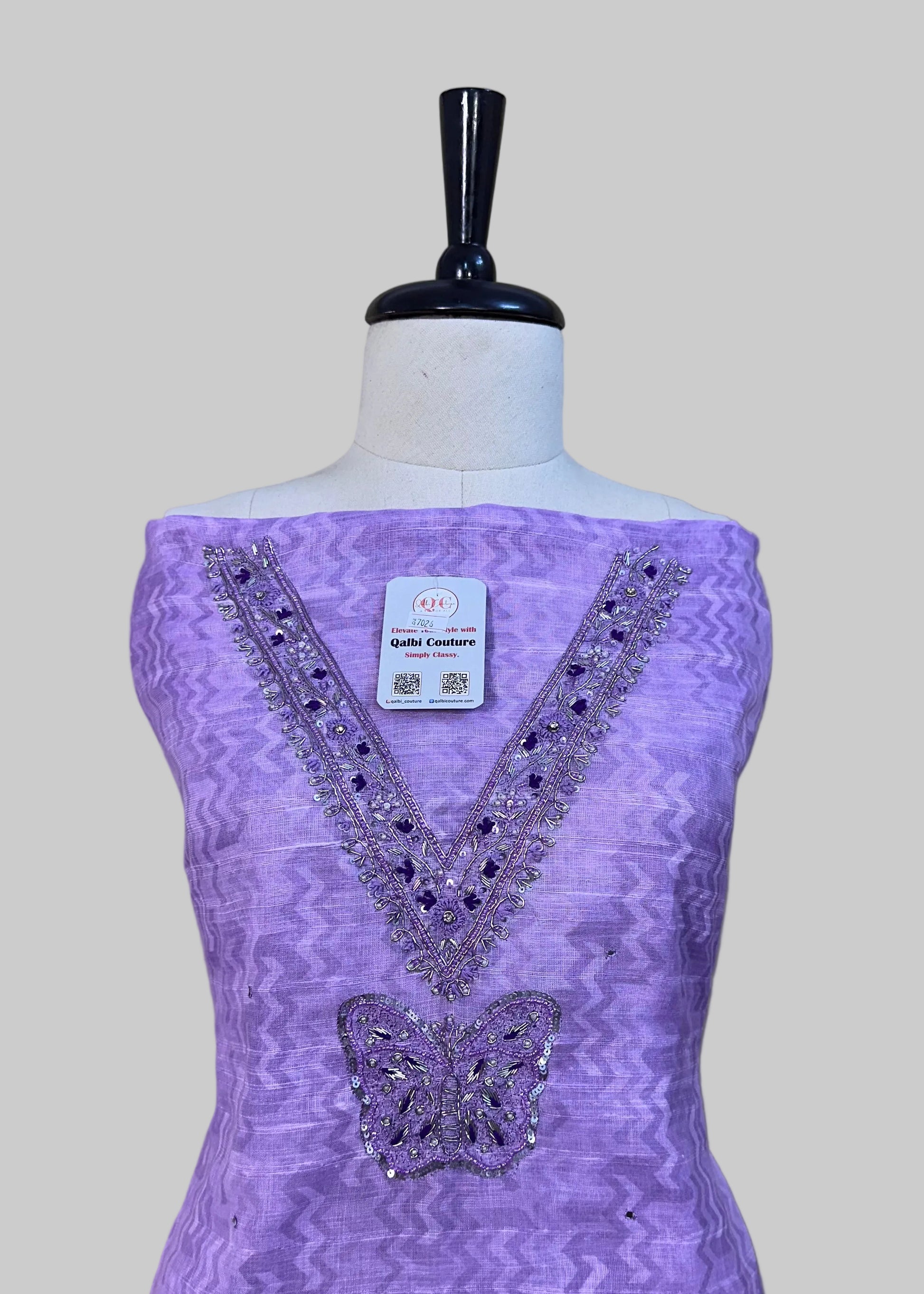 Purple dress with butterfly design on a mannequin against a beige background