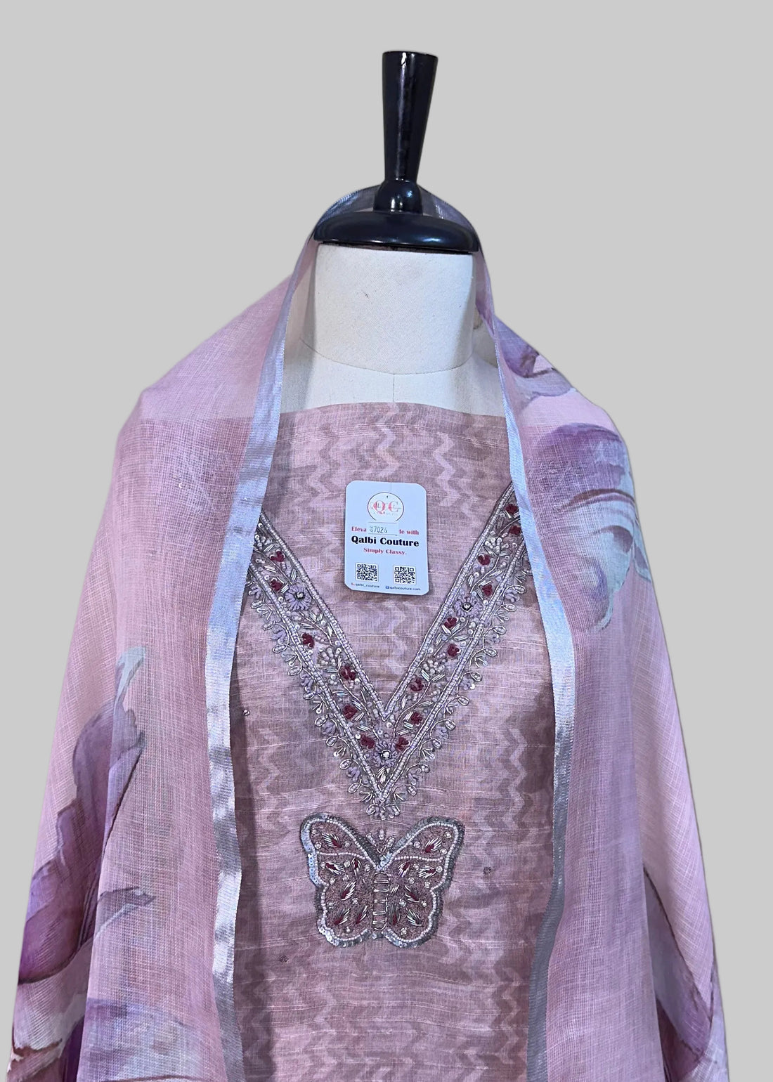 Mannequin wearing a pink dress with a matching shawl on a beige curtain background