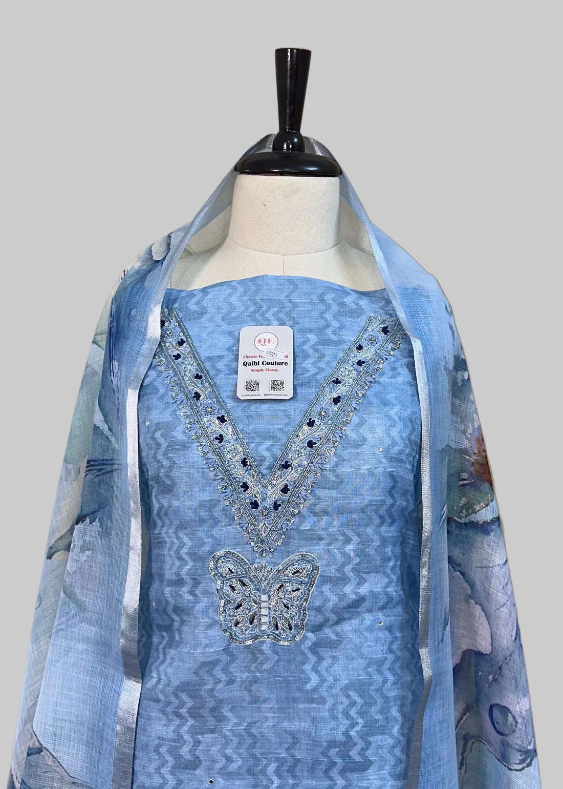 Blue embroidered dress on a mannequin against a beige background