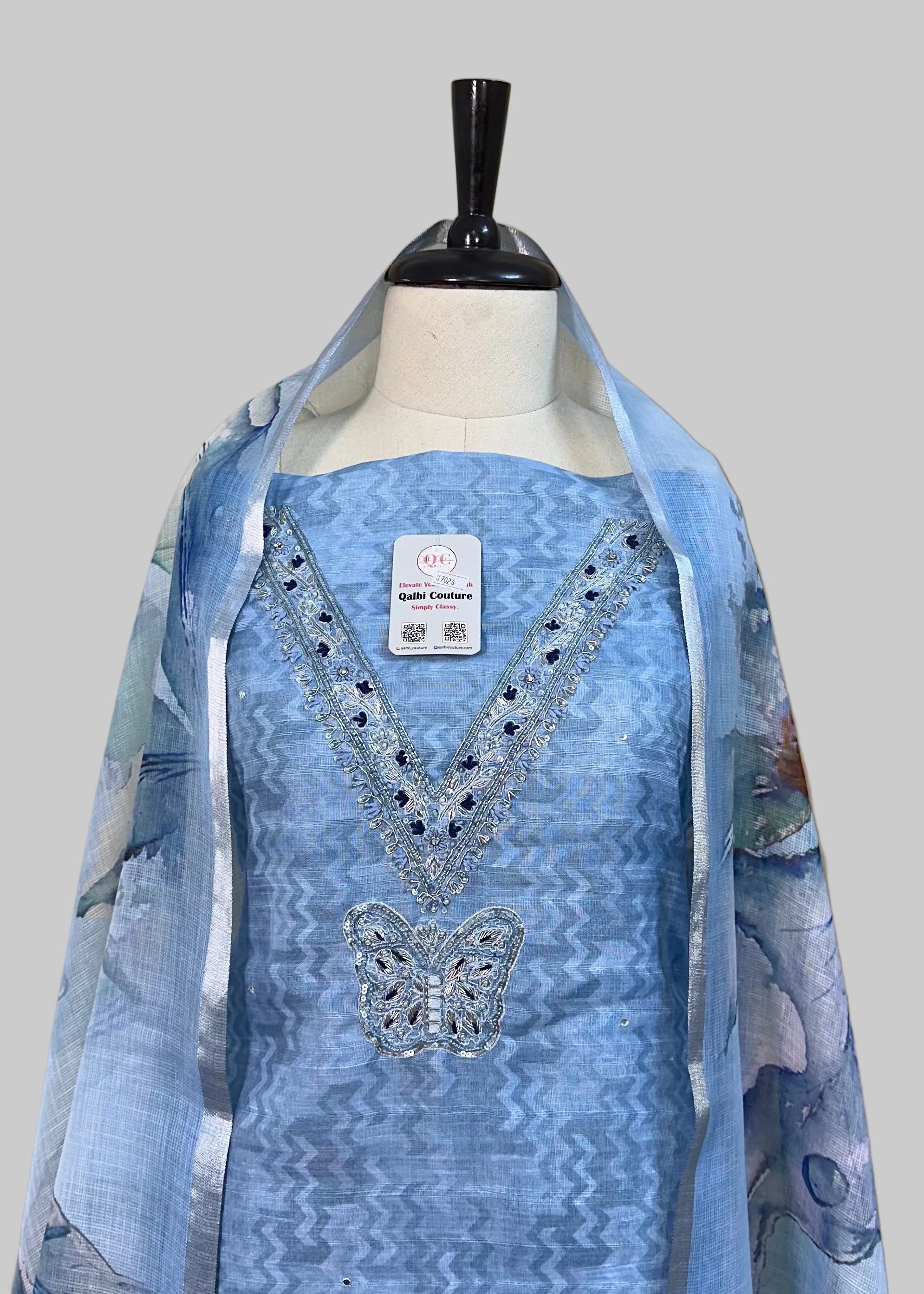 Blue embroidered dress on a mannequin against a beige background