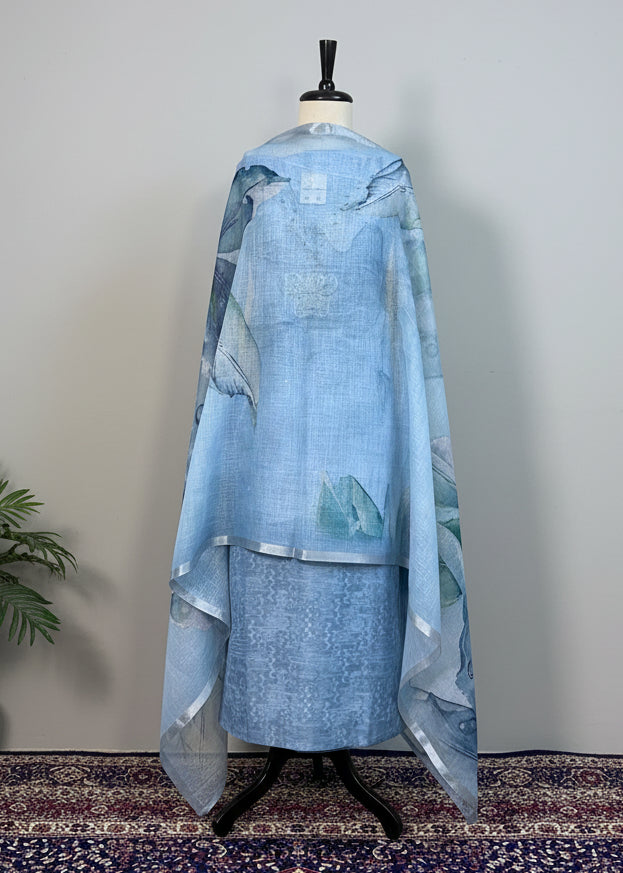 Mannequin wearing a light blue traditional outfit with a patterned rug and beige curtain background