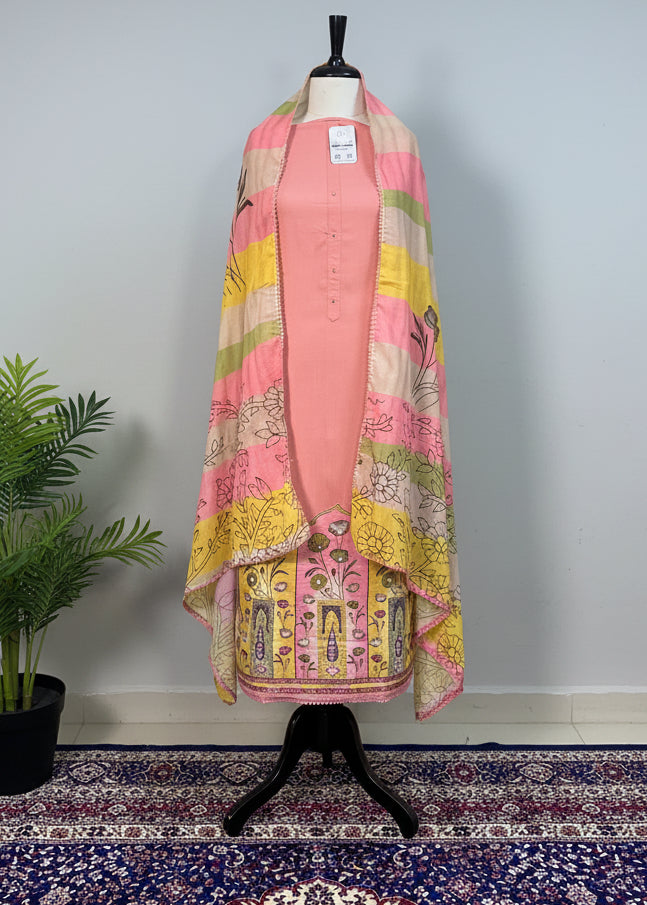 Mannequin wearing a pink outfit with a colorful patterned shawl against a beige curtain.