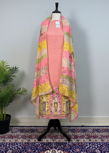 Mannequin wearing a pink outfit with a colorful patterned shawl against a beige curtain.