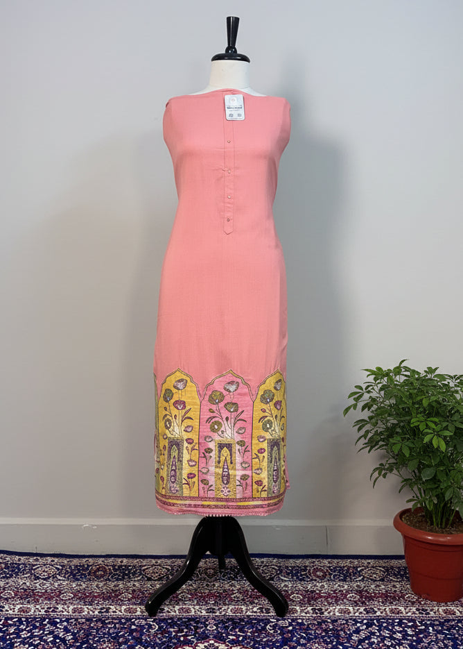 Pink dress with embroidered hem on a mannequin against a beige curtain.