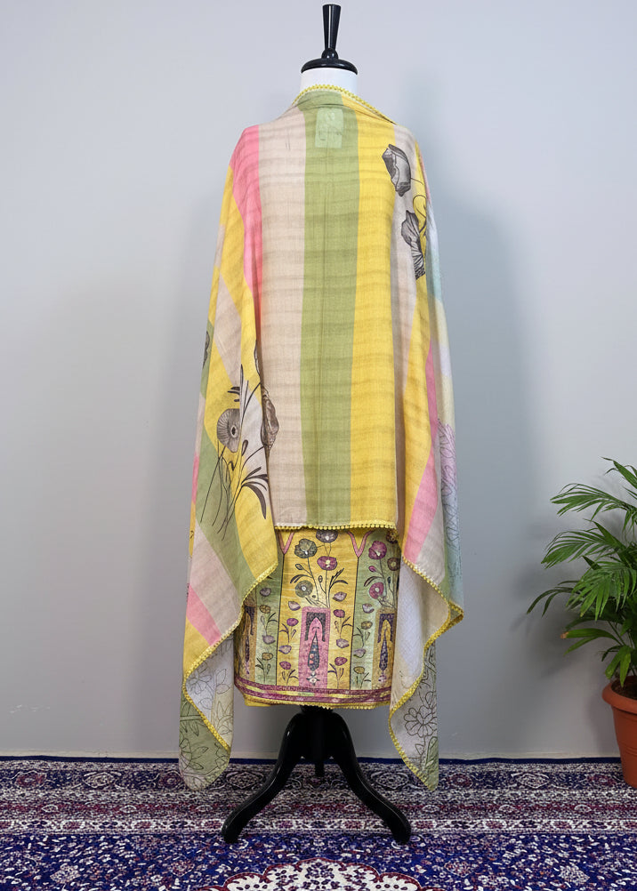 Mannequin wearing a yellow outfit with a colorful scarf against a beige curtain background
