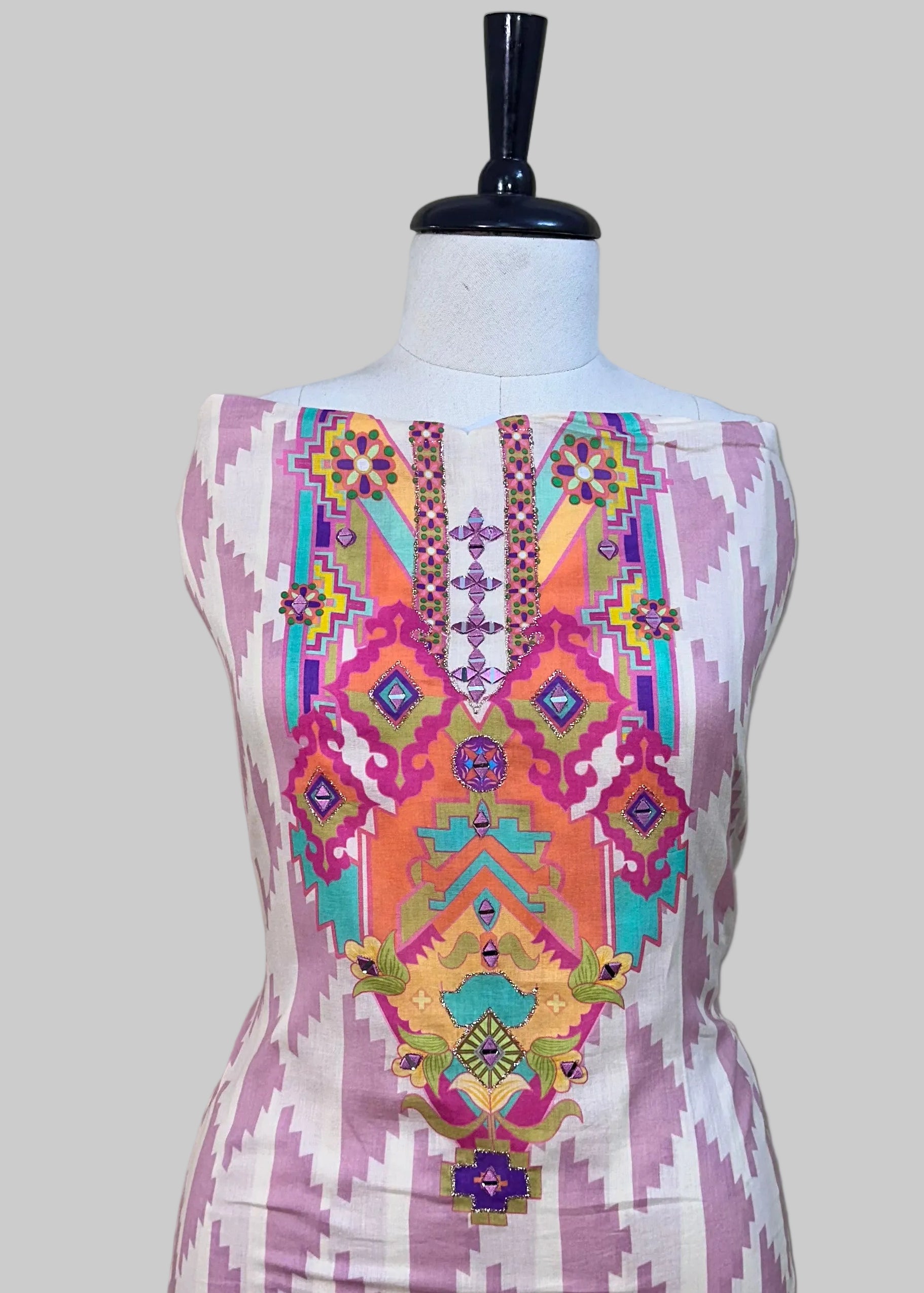 Colorful embroidered dress on a mannequin against a plain background